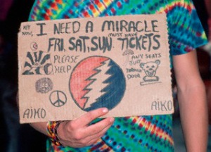 September 1987 --- A fan of the band Grateful Dead holds a handmade sign reading I need a miracle, hoping to get tickets to a Grateful Dead show. --- Image by © Lynn Goldsmith/Corbis